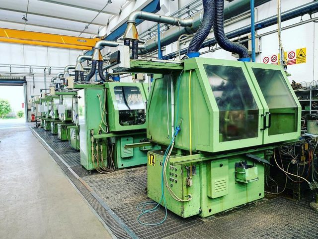 In questa foto si vedono dei macchinari grandi di colore verde in fila uno dietro l'altro per le minuterie meccaniche Bergamo
